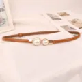 Detail shot of elegant thin brown leather dress belt with white pearl buckle decoration - Camel