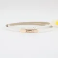 Dettaglio sottile cintura bianca in pelle con fibbia dorata, accessorio minimalista chic. - Bianco