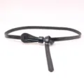 Detalle de un cinturón de cuero negro para mujer con nudo elegante para estilizar la silueta. - Negro