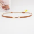 Minimalistische smalle bruine lederen damesriem met gouden metalen gesp elegant accessoire. - camel