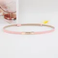 Minimalistische roze dunne lederen damesriem met gouden metalen gesp, stijlvolle tailleaccessoire. - Roze