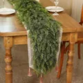Detail view of a lush Norfolk pine artificial garland on a wooden dining table. - 1.8m / 33 Heads