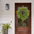 Weergave van een kleurrijke wilde bloemenkrans hangend aan een rustieke houten voordeur. - 40CM