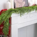 Detail van realistische Norfolk dennenslinger op een witte open haard voor Kerstmis decoratie - 1.8m 13-Tandige Dennen Slinger (52 Takken)