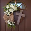 Detailed view of an Easter wreath with white lilies and a wooden cross on a brown door. - Cross Wreath (Without Scarf) / 40CM