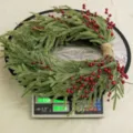 60cm Christmas wreath with red berries on a scale showing 0.720kg weight - Premium Material Pine Wreath