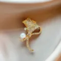 Elegant gold ginkgo leaf brooch detail, shining rhinestones and white pearl embellishment. - Gold
