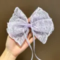 Vista detallada de una elegante horquilla de lazo de encaje morado taro con cintas delicadas. - Púrpura Taro