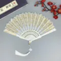 Chinesischer Faltfächer mit goldener Spitzenmusterung, eleganter weißer Quaste und Anhänger. - Weiß mit Quaste