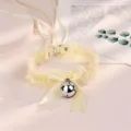 Vue détaillée d'un collier choker en dentelle jaune clair douce avec un joli nœud et cloche. - Collier Seul / Jaune
