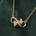 Detailed shot of gold infinity butterfly pendant necklace with sparkling cubic zirconia on fine chain. - X5880-1 Style