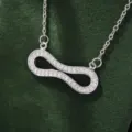 Detailed closeup of a sparkling cubic zirconia infinity pendant necklace on green velvet display. - X5877-2 Style / Silver