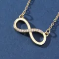 Closeup detail of gold infinity symbol necklace pendant sparkling zirconia crystal refined link. - X5883-1 Style