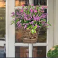 Hanging wicker basket with vibrant pink wildflowers and lush greenery for home door decor. - Spring Pink Flower Basket / 35*20*8cm