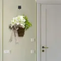 Künstlicher weißer Hortensienkorb mit gepunkteter Schleife an einer hellgrünen Wand hängend - 35x20x8cm / Weißer Hortensien-Blumenkorb