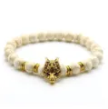 Detailaufnahme des weißen Steinperlenarmbands mit goldenem Wolfskopf-Anhänger und Abstandhaltern. - Goldener Wolfskopf / Weiß