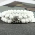 Detailopname van witte kralen dubbele armbandset met metalen Boeddha-hoofd en buisbedels. - Kleur 7