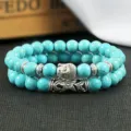 Close-up detail van de dubbellaagse turquoise kralenarmband met zilveren boeddha hoofd charm. - Kleur 9