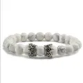 Vue détaillée du bracelet de perles en pierre blanche avec de charmants pendentifs couronne. - Howlite