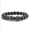 Gros plan détaillé du bracelet de perles noires avec de charmantes couronnes métalliques. - Hématite