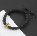 Close-up detail van zwarte lavasteen kralenarmband met een gouden spartaanse helm. - 14