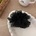 Elegante zwarte mesh scrunchie met ruches op een decoratief wit schelpenbordje - Zwart