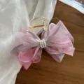 Eleganter Haarklammer mit rosa floraler Netzschleife und Perlendekor auf Holztisch - Rosa