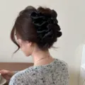 Gros plan détaillé d'une grande pince à cheveux en tissu noir plissé sur un chignon de femme. - Style en Cuir Souple Noir (260403)