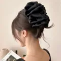 Nahaufnahme einer eleganten schwarzen Haarklammer aus Satin, gestylt im braunen Haar - Gipskraut Geometrisch / Schwarz