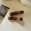 Zwei elegante dunkelbraune Haarklammern mit Satinschleife auf Hintergrund - 2 Stück/Set / Braun
