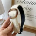 Elegant cream knitted headband with amber ring for winter hair styling. - Off White