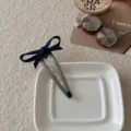 Elegante pinza para el cabello con lazo azul marino y gemma azul en una bandeja blanca - Estilo Gota de Agua