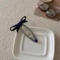Pinza para el pelo coreana con lazo azul marino y gema azul sobre una base gris - Ovalado