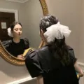 Detailopname van een model met een elegante grote witte tule strik als haaraccessoire. - Grote Stijl / Wit