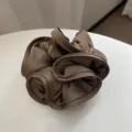 Détail rapproché d'un chouchou en satin marron café avec d'élégants bords ondulés. - L / Café Clair