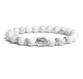 Close-up detail of the white beaded bracelet featuring a silver Buddha head and metal spacers. - White Round Bead