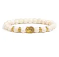 Closeup of the 8mm white stone bead bracelet showing the detailed golden Buddha head charm. - White Crackle Stone