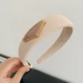 Minimalist beige padded headband featuring a gold-rimmed triangle fashion plaque - Milk Tea