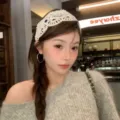 Serre-tête en crochet blanc fait main porté par un modèle dans un café cosy - Tissage en Tissu Ajouré Beige