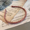 Elegant terracotta velvet pleated headband with thin wrapped texture on vintage music sheet. - Flat Style / Pink
