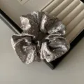 Coletero de satén gris plateado con pedrería brillante en una bandeja de joyas - Coletero / Gris