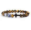 Close-up detail of tiger eye stone bead bracelet with black cross pendant and blue stone. - 24