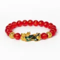 Vue détaillée du bracelet Pixiu en agate rouge 8mm avec perles de mantras dorés et charme chanceux. - Agate rouge