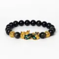 Détail de bracelet en perles d'obsidienne avec charm Pi Xiu doré et perles de pierre noire. - Obsidienne