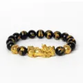 Détail de bracelet en perles noires avec charm Pixiu doré et motifs sculptés élégants. - Obsidienne 9
