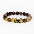 Gros plan détaillé des perles en agate et du charm Pixiu doré sur bracelet élastique. - Obsidienne Acajou