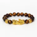Gros plan détaillé du bracelet en perles d'œil de tigre avec pendentif Pixiu doré. - Œil de Tigre 17
