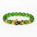 Détail du bracelet de perles vertes avec charm Pixiu doré et symboles de mantra gravés. - Vert