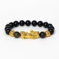Gros plan détaillé du bracelet de perles noires avec un charm Pixiu doré et des perles d'accent. - Obsidienne Dorée 21
