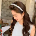 Eleganter hellblauer geflochtener Haarreif mit Kristallen getragen von einem asiatischen Model - Verschwommenes Blumenmuster / Blau